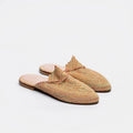 A pair of woven slip-on mule sandals with a textured multicolor pattern of beige, orange, and green threads, featuring a light pink insole and a dark brown outsole, set against a plain white background.