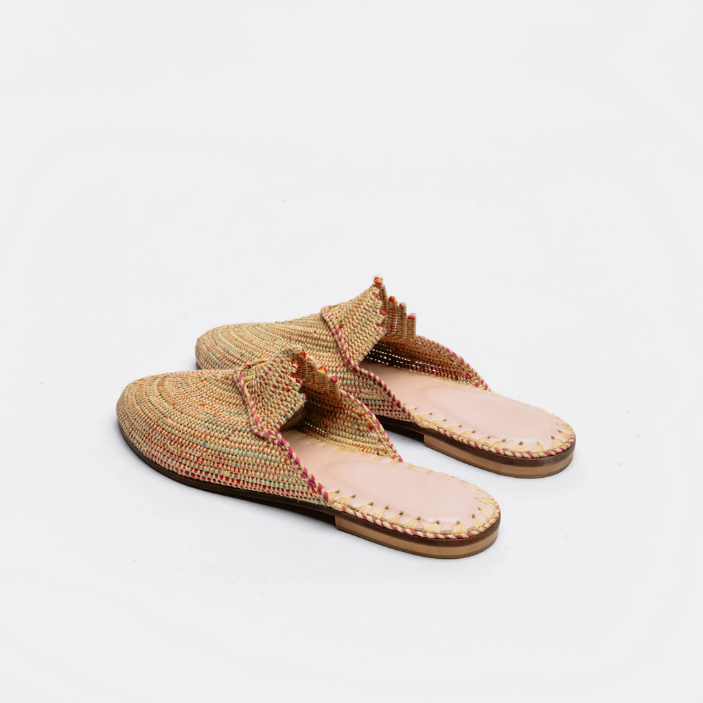 A pair of woven thong-style mule sandals in a multicolor tan, beige, and brown pattern with a light pink footbed and brown soles, photographed on a clean white background.
