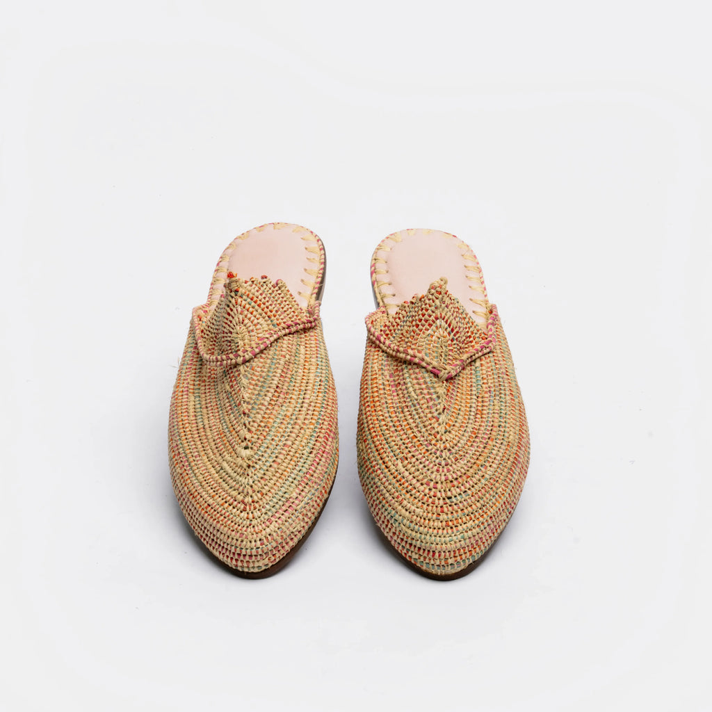 A pair of woven pointed-toe mule slippers in a multicolor pattern of orange, green, and beige, shown from a top-down view on a white background.