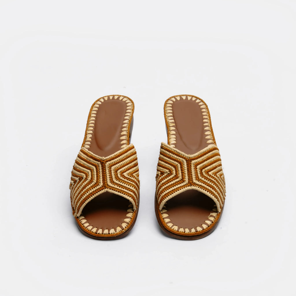 A pair of women's open-toe slide sandals with geometric braided straps in brown and beige, set against a plain white background.