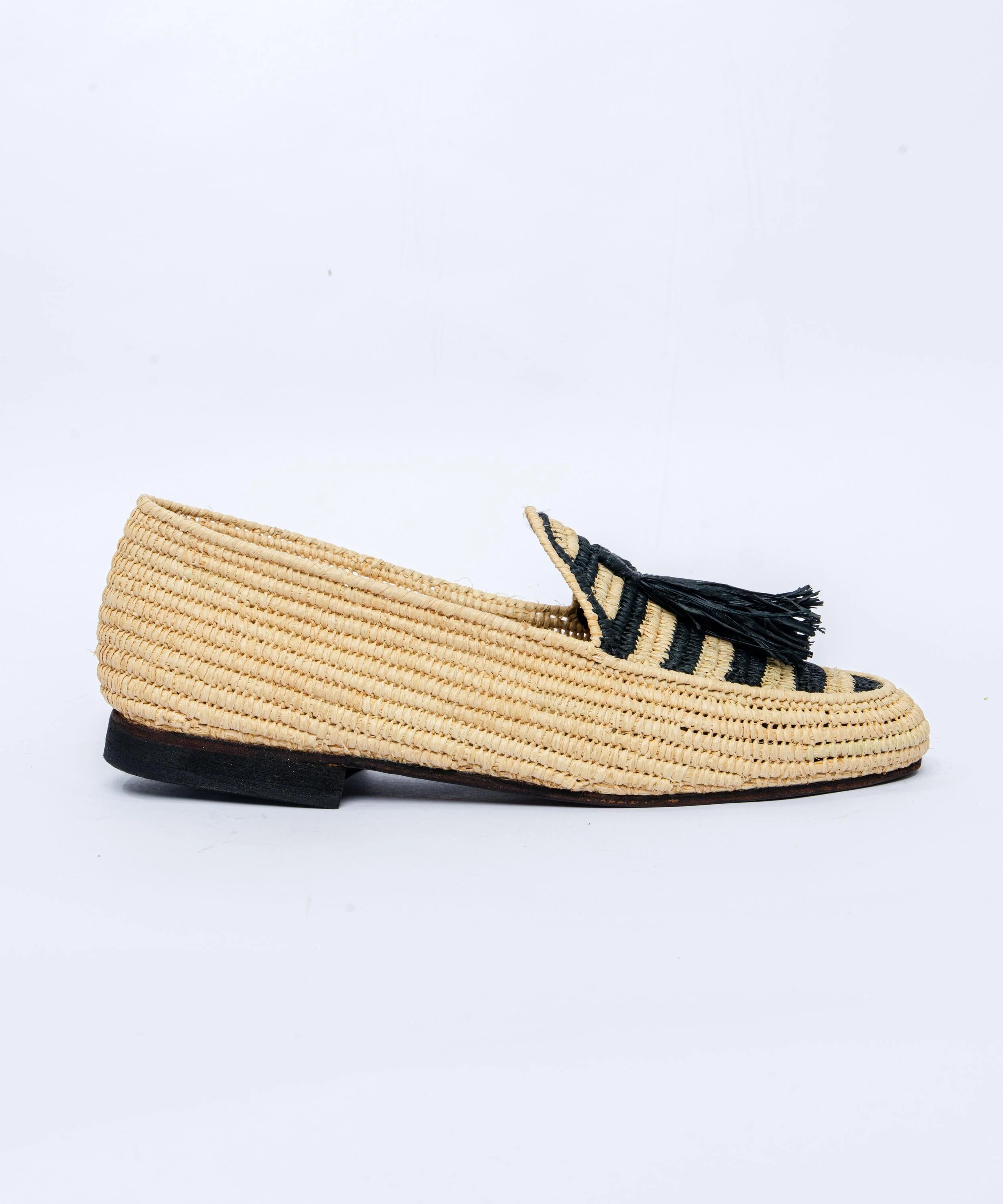 Beige woven loafer with black tassel on a white background