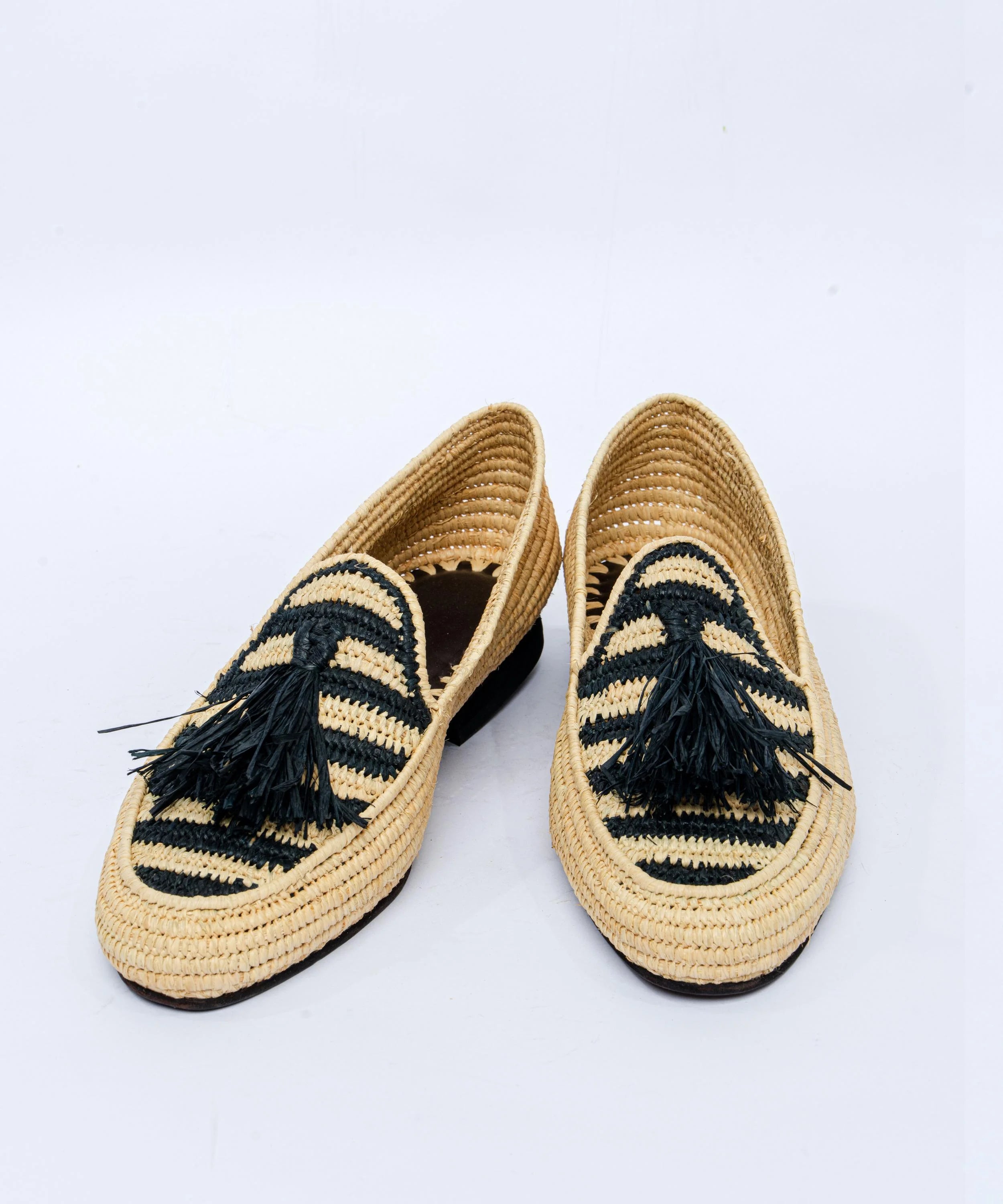 Pair of woven shoes with black tassels on a white background