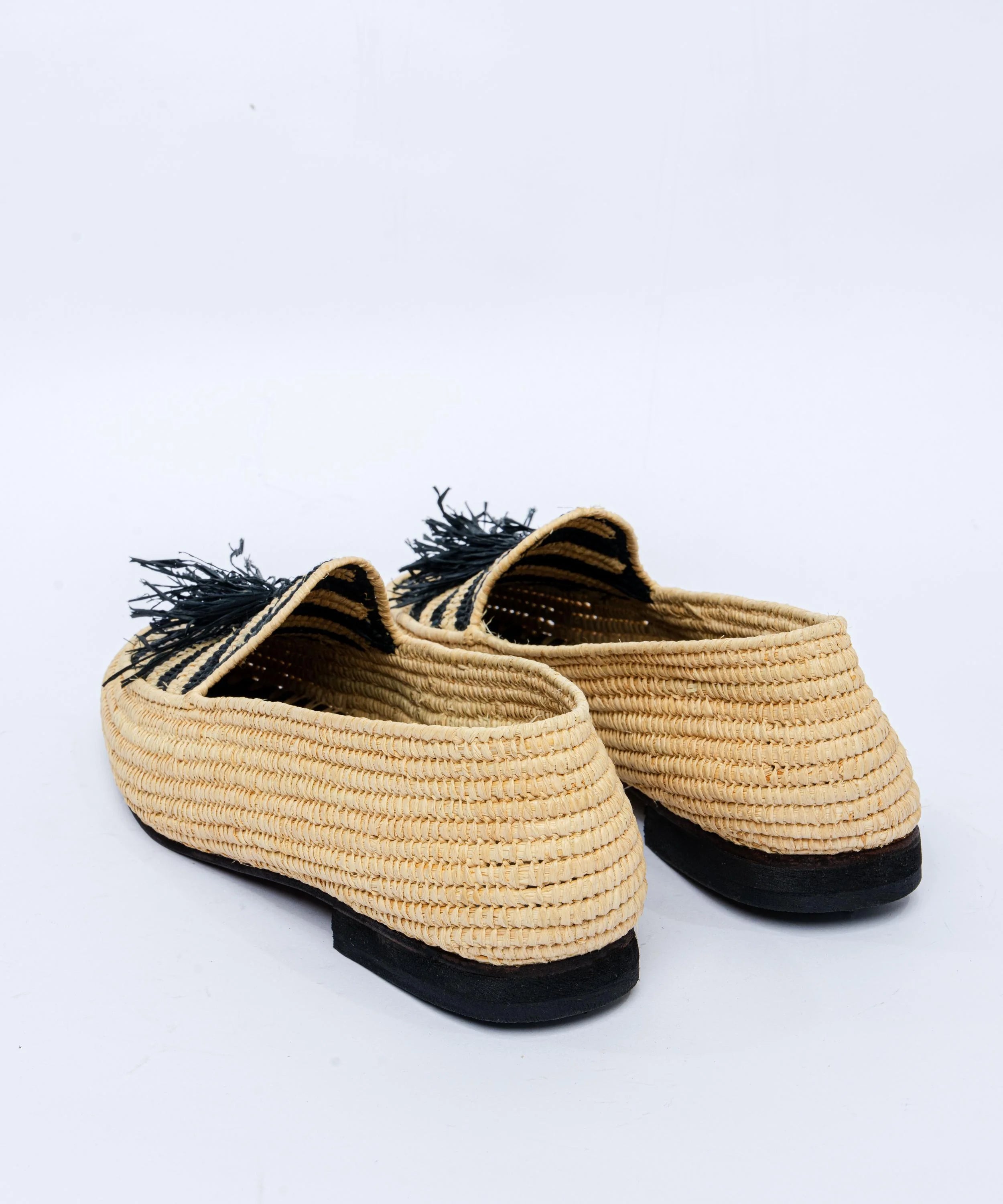 Pair of woven shoes with black soles on a white background