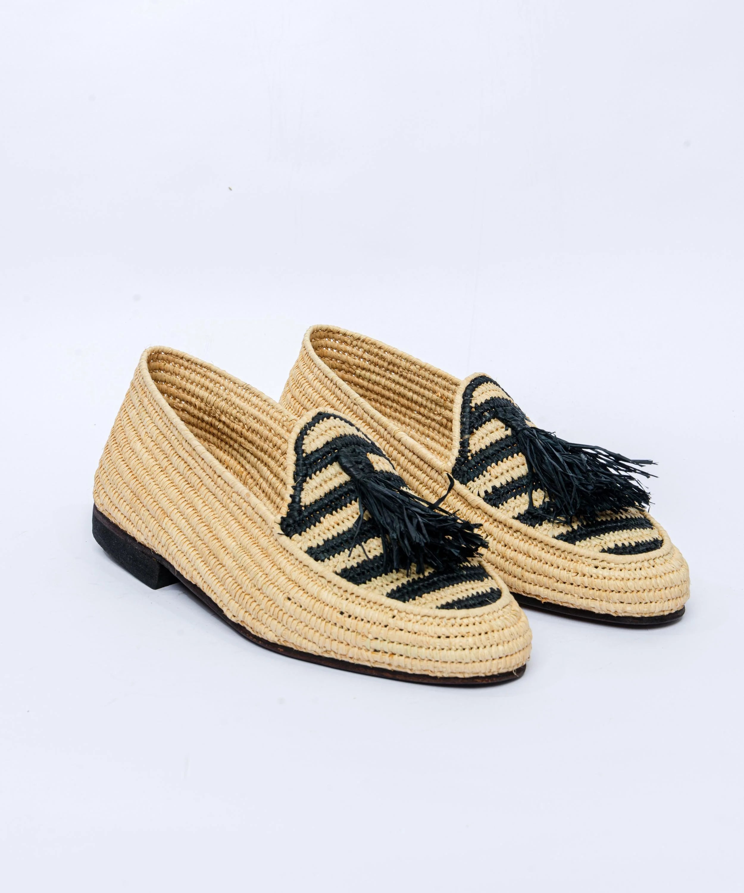 Pair of woven shoes with black accents on a light gray background